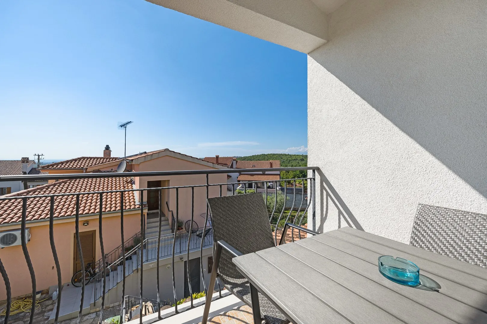 The view from the upper balcony over terracotta rooftops towards wooded countryside