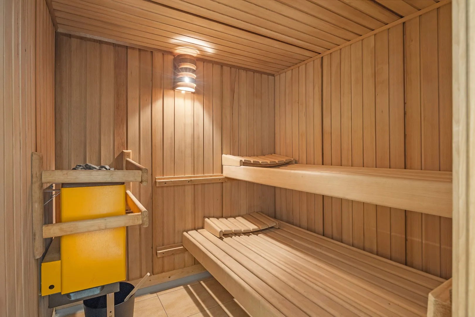 Inside the wood-lined sauna, with two tiers of slatted benches and the heater in the corner