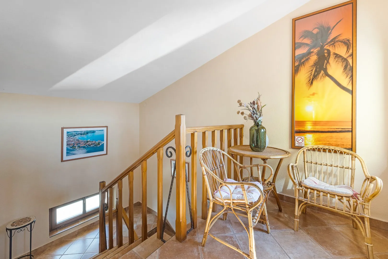 The upper landing, cane chairs and a small table beside the stairwell
