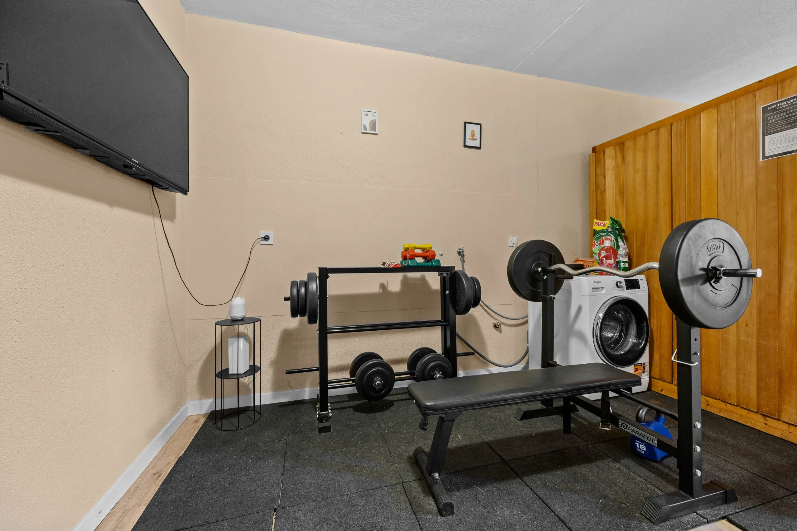 The weights bench, barbell and dumbbell rack on the gym's matted floor