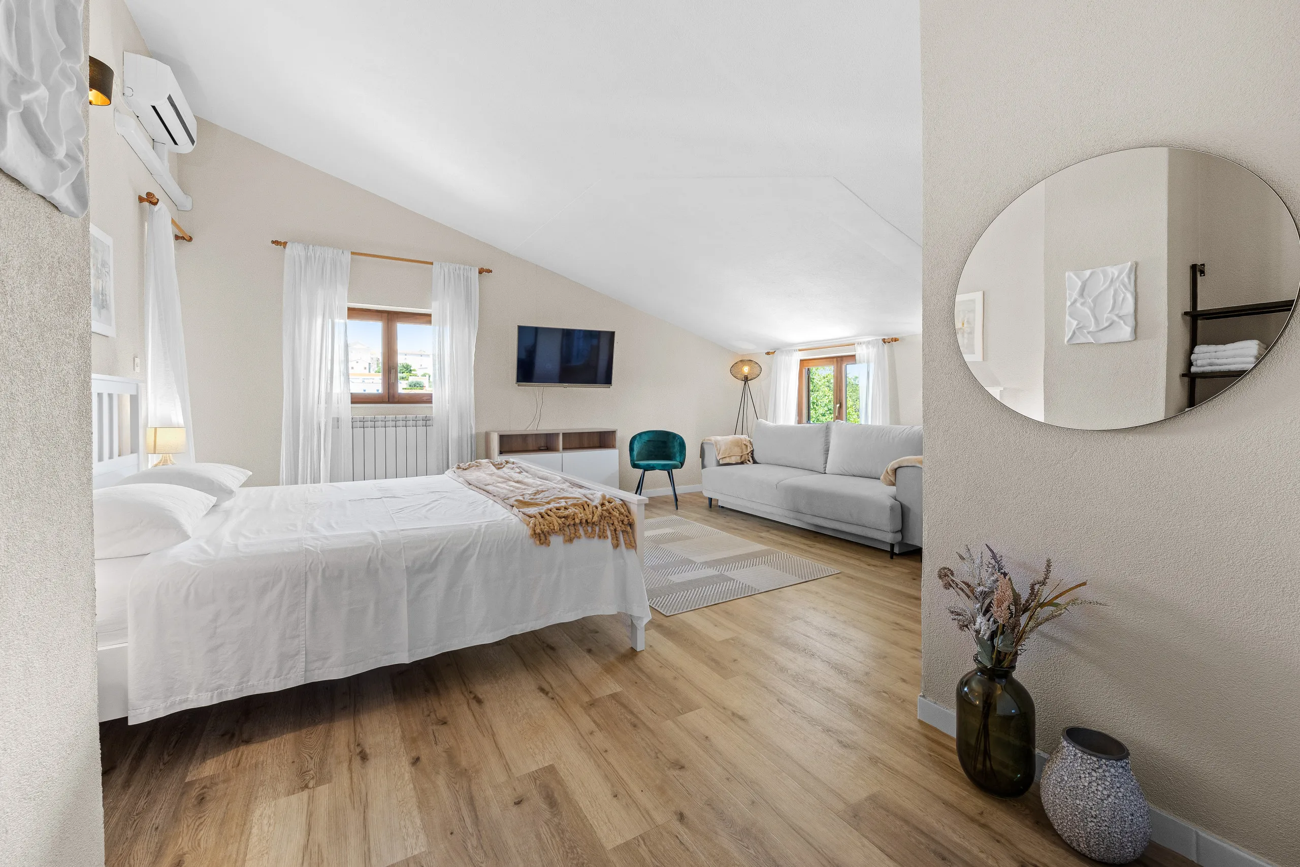 A large loft room with a double bed at one end and a sofa and television at the other