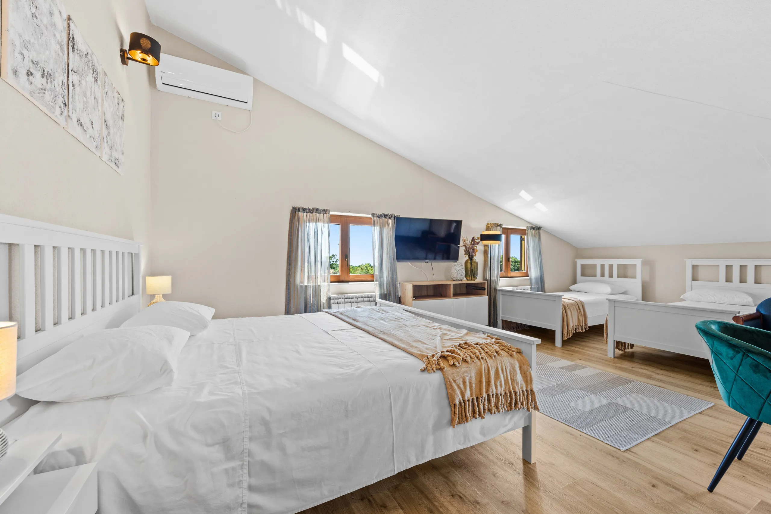 A family room under a sloping ceiling: a double bed with two singles across the floor