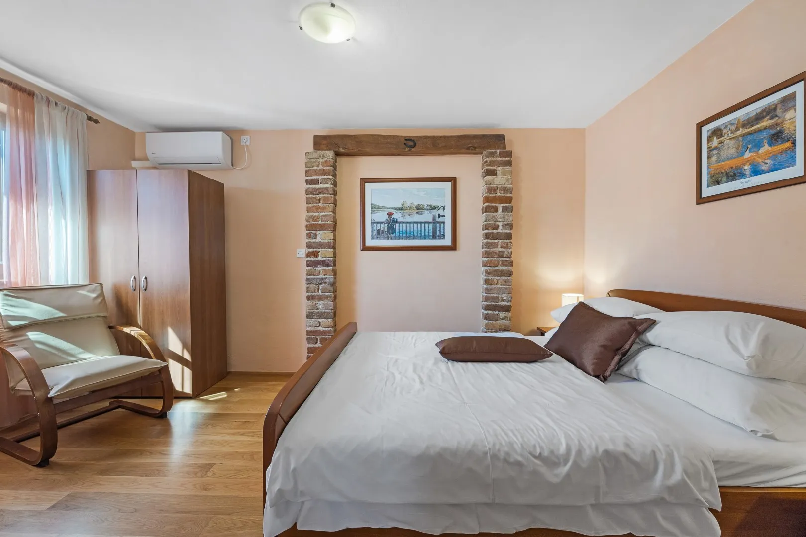 A double bed set into a brick-framed alcove in an apricot-walled room