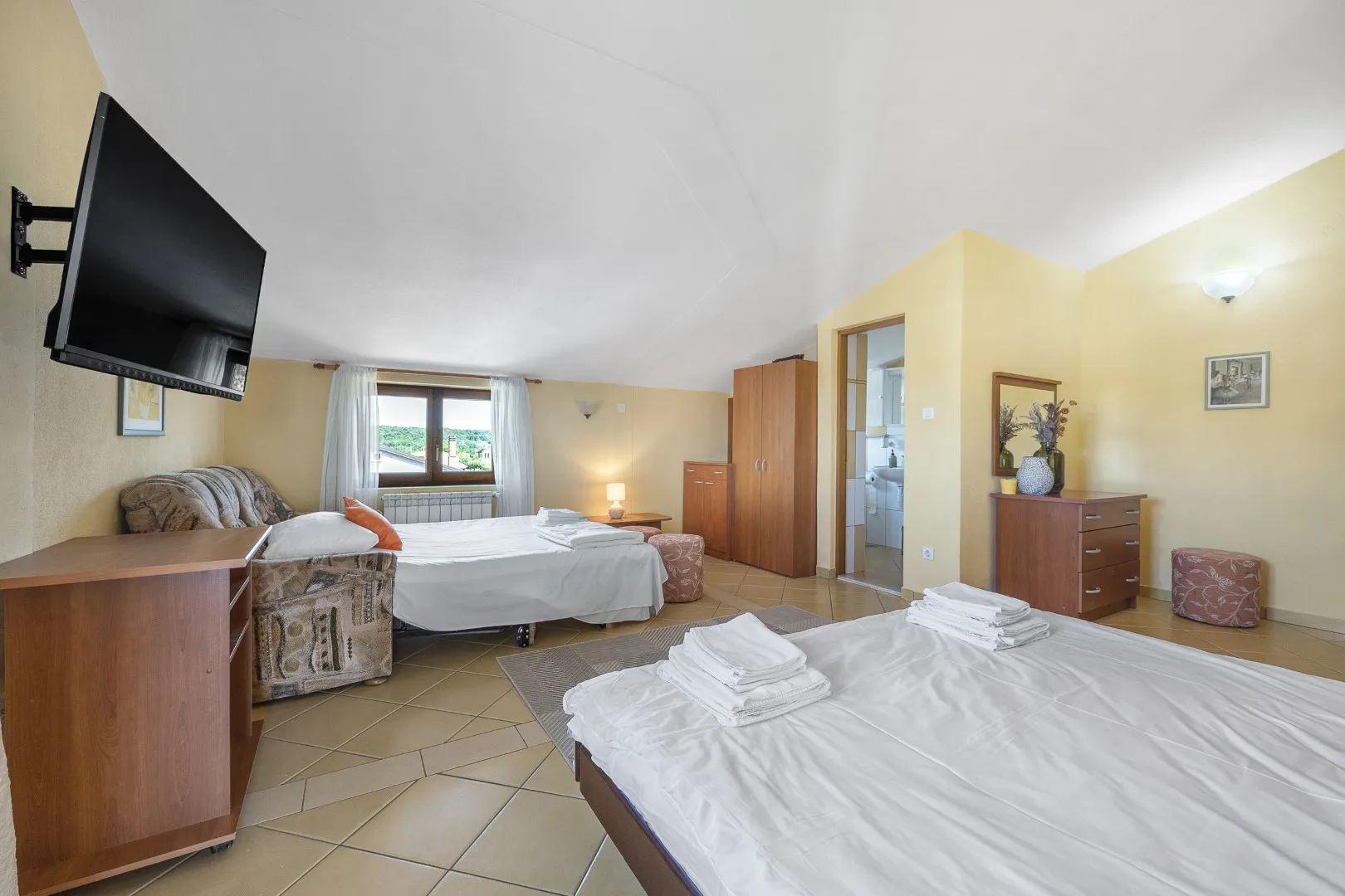 A large room with two double beds, a tiled floor and its own bathroom through the doorway