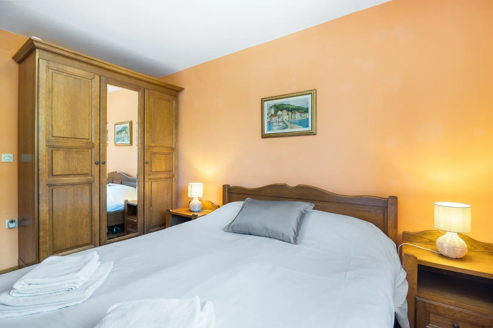 A double bed with a carved oak headboard and a mirrored wardrobe alongside
