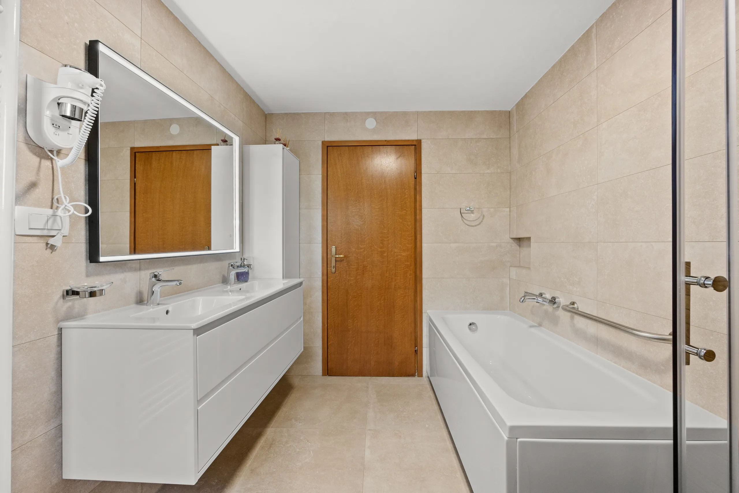 A long bathroom with a double vanity and a bath along the far wall