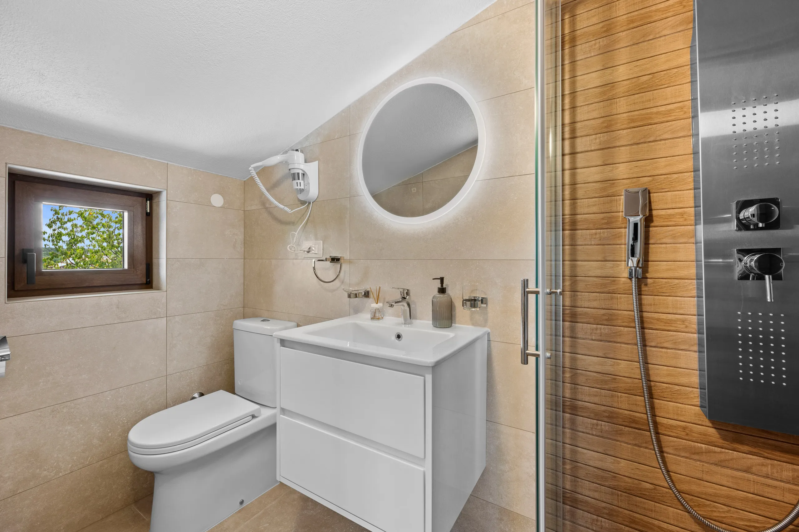 A shower room with a round mirror, a small window and an oak-lined shower